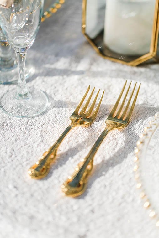 Gold flatware and textured white linen styled table detail